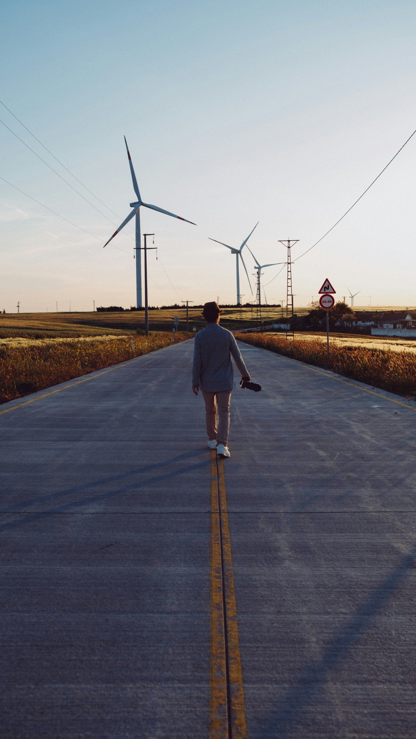 A person walking down a road with windmills in the background