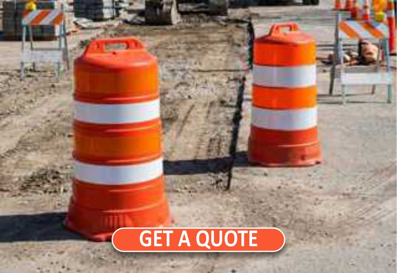 Roadmax high-visibility orange work zone traffic drums deployed on a highway construction site